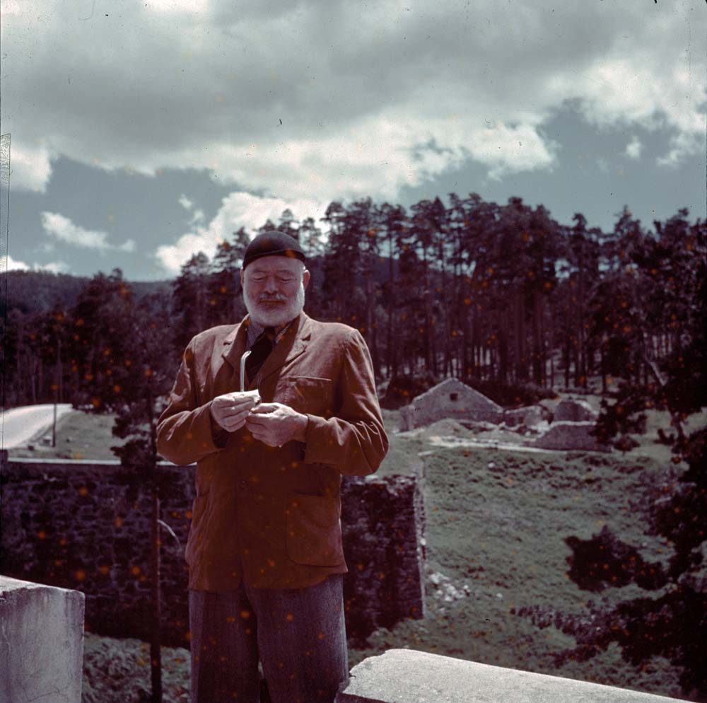 EH-C271T 1959/nd Ernest Hemingway cleans his glasses outdoors. Red spots original to transparency.