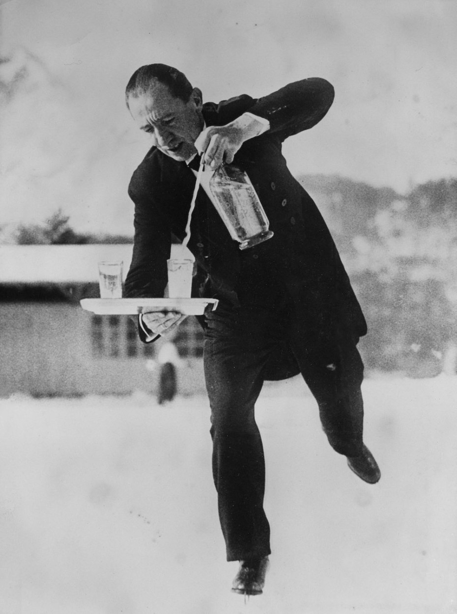 SWITZERLAND - JANUARY 01: Waiter on skates on skating rink, pouring soda water into a glass which he is balancing on a tray. Photography. Switzerland. St. Moritz. About 1935. (Photo by Imagno/Getty Images) [Kellner auf Schlittschuhen auf dem Eislaufplatz, aus einer Siphonflasche in ein Glas, das er auf dem Serviertablett balanciert, Sodawasser einschenkend. Photographie. Schweiz. St. Moritz. Um 1935.]