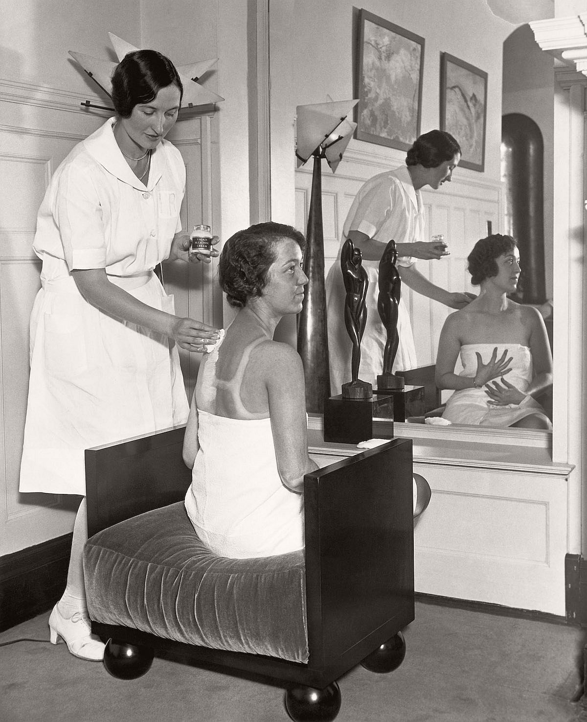30 Sep 1929, Chicago, Illinois, USA --- In the fashionable Gold Coast salon of Helena Rubenstein, Carolyn Lang applies lotions to Billie Gloss' suntanned back, bleaching it down so that Miss Gloss will be the same pale shade all over. --- Image by © Underwood & Underwood/Corbis