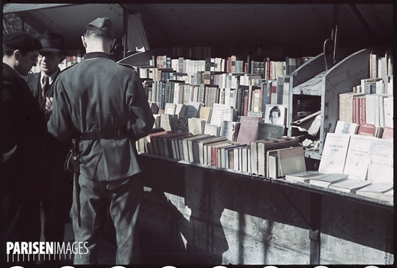 Guerre 1939-1945. Soldat allemand feuilletant des livres des bouquinistes du quai Voltaire. Paris. Photographie d'AndrÈ Zucca (1897-1973). BibliothËque historique de la Ville de Paris.