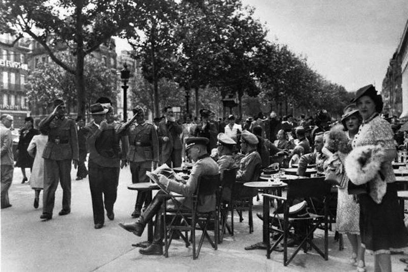 German officers and Parisians mingle near a sidewalk cafe on the Champs Elysees on Bastille Day in 1940. The German armed forces occupied France earlier that year. July 14, 1940 Champs Elysees, Paris, France